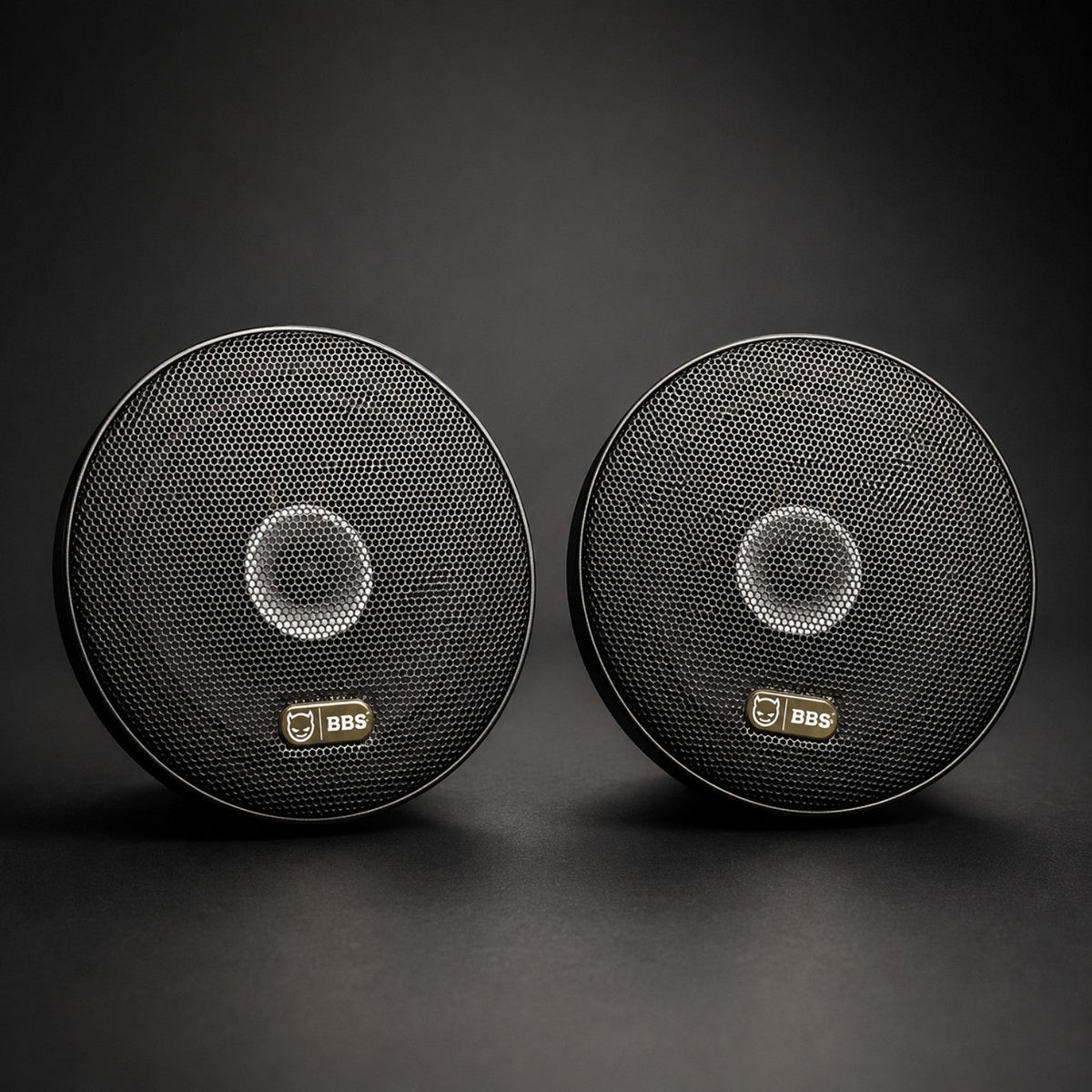 Pair of BBS Inferno 65CXN speaker grilles on a black studio background